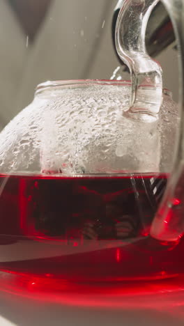 preparar té de hibisco en una tetera en la mesa. preparación cuidadosa de té de hierbas nutritivo utilizando el flujo caliente de la olla eléctrica por la mañana. ritual familiar