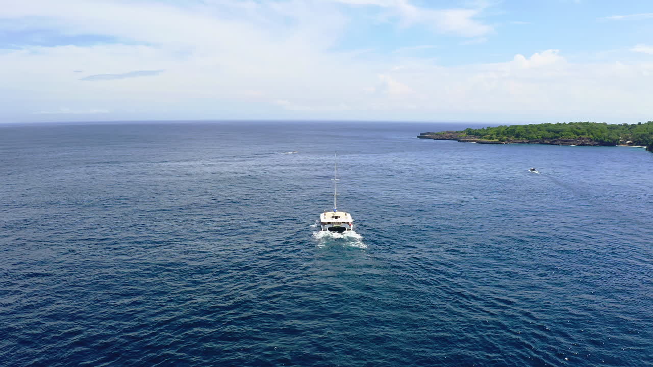 barco catamarán navegando en las aguas del mar azul a lo largo de la costa de bali
