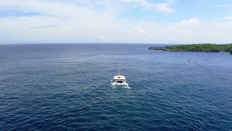 Catamaran-boat-sailing-in-blue-sea-waters-along-coast-of-Bali