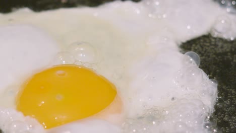 close up of fried egg sunny side up with pockets of air after heat from the oil. cooking protein rich breakfast healthy food