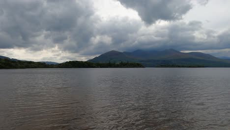 lake side rolling mountain landscape under heavy overcast cloud