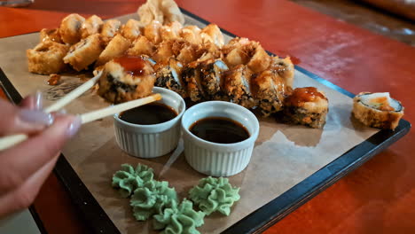 Hand-serving-sushi-with-chopsticks-closeup-above-red-restaurant-table-caucasian-hand-and-Wasabi