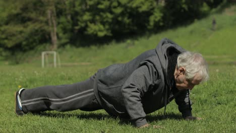 active senior old man do push-ups physical exercises in sport playground