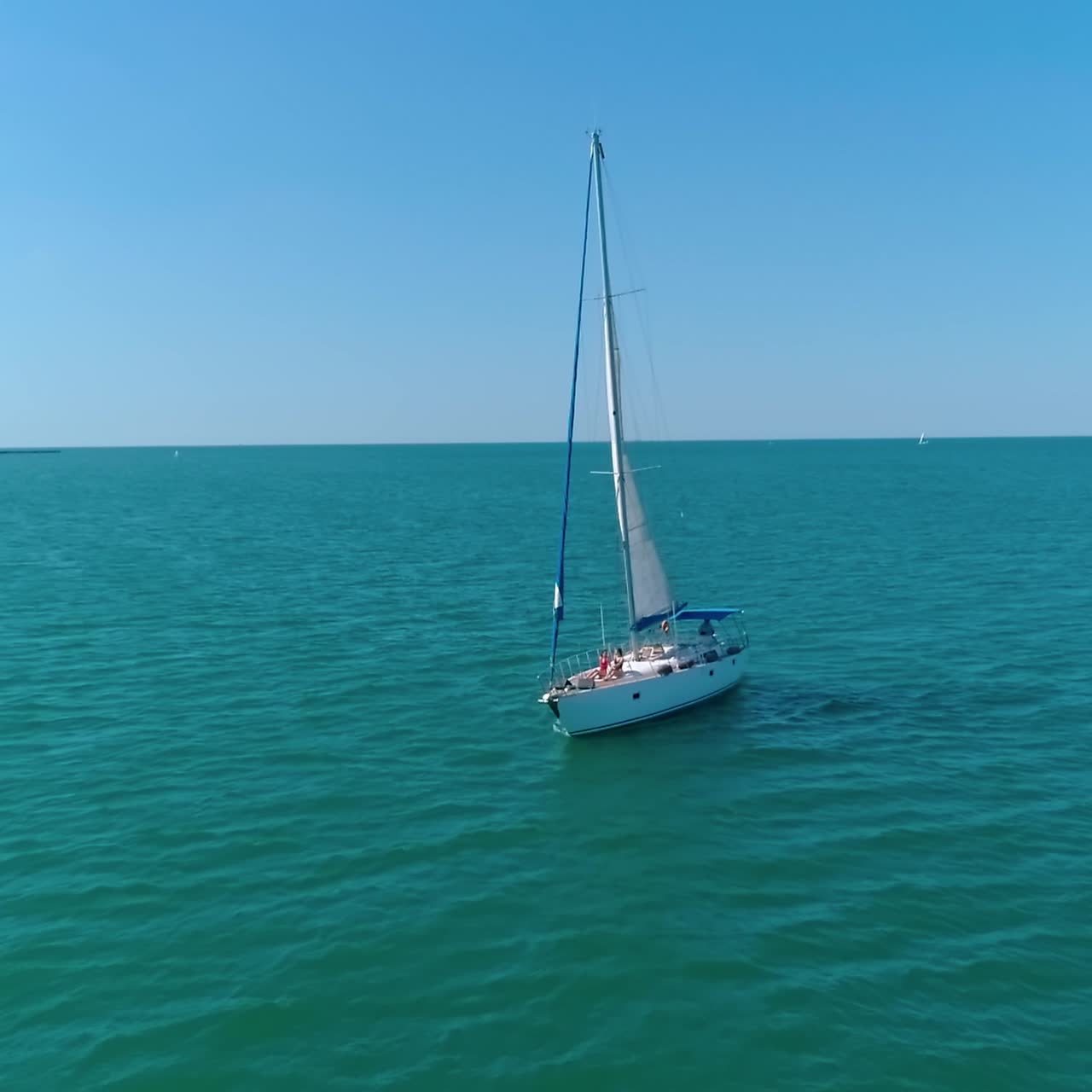 People rest on a luxury yacht. Sailboat under white sail floating on the open sea. Beautiful yacht sail on a seascape. Women relax on boat at summer cruise. Camera rising