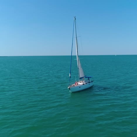 people rest on a luxury yacht. sailboat under white sail floating on the open sea. beautiful yacht sail on a seascape. women relax on boat at summer cruise. camera rising