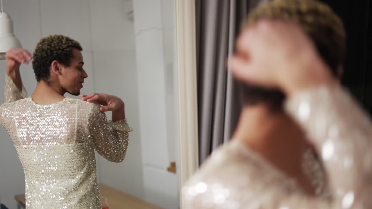 드레스를 입은 남자가 거울 앞에 서서 천천히 춤을 추고 있습니다.