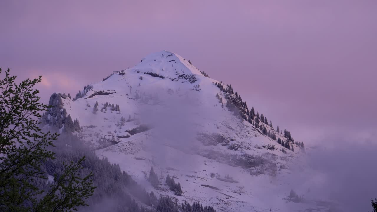 punto pico de la montaña de nyon timelapse durante una puesta de sol de invierno rosado y púrpura y nubes bajas convirtiéndose en una noche clara