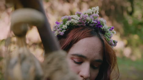 young girl holding her druidic staff wearing a crown of flowers close shot