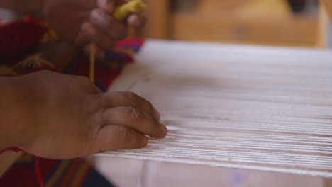 A-women's-hands-weaving-on-a-loom-to-create-a-tapestry