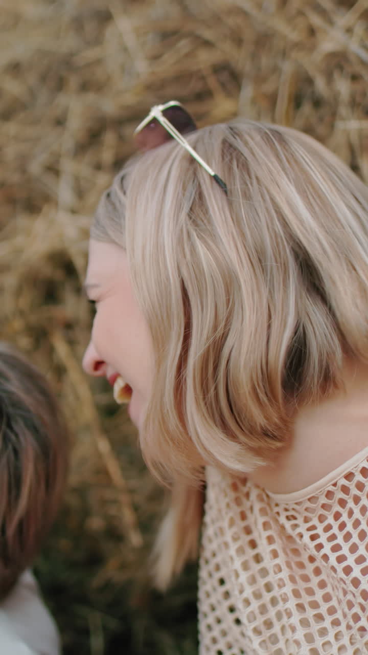 행복한 여자가 에 웃는 친구와 함께 기게 웃고, 광활한 농경지로 둘러싸여, 밝은 야외 설정은 행복으로 가득 찬 즐거운 순간을 포착합니다.