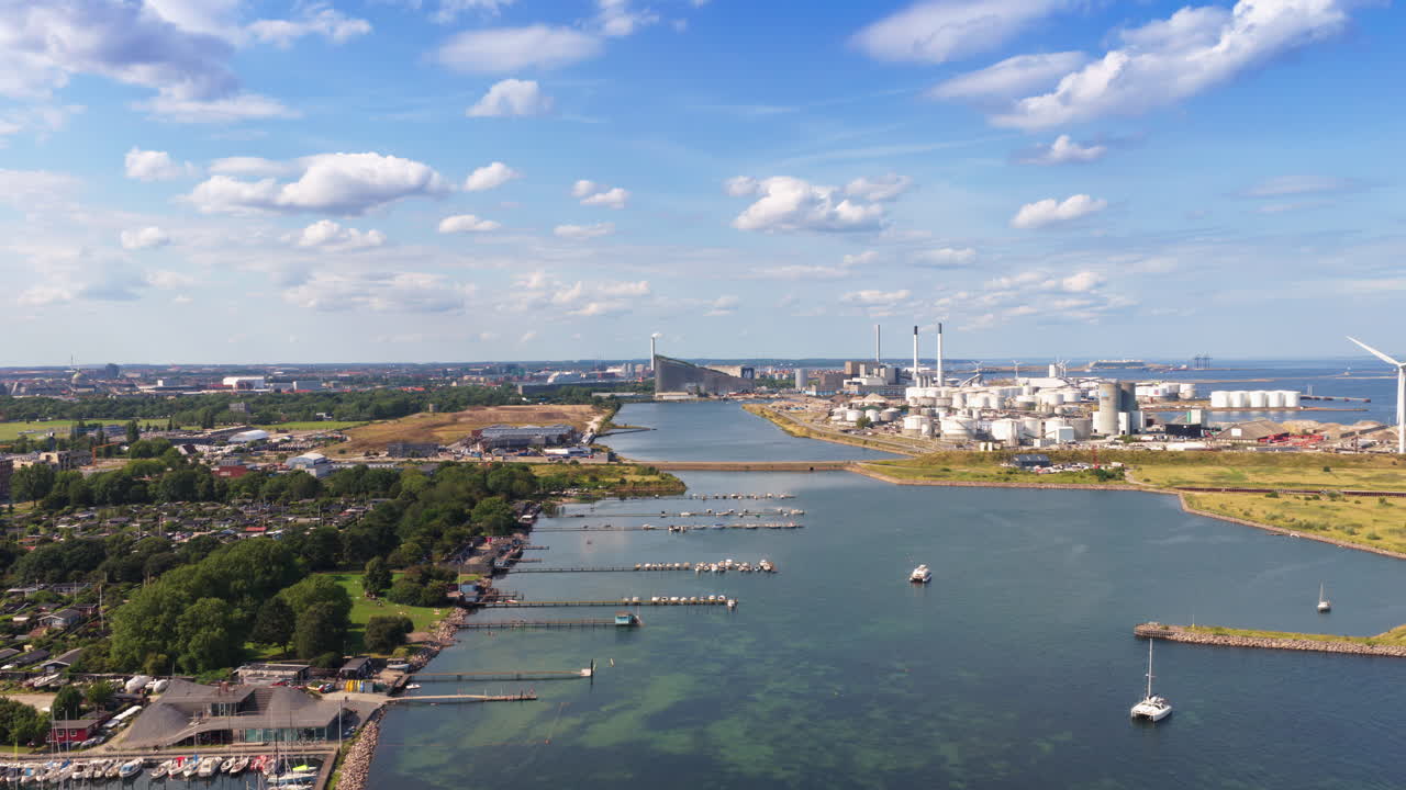 Aerial drone view of the coastline near Amager Strandpark, with sailboats in the water and CopenHill visible in the distance in Copenhagen, Denmark