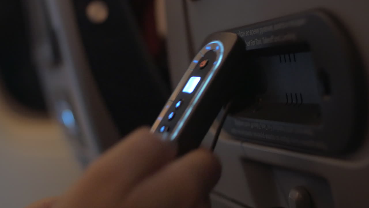 женщина, использующая контроллерный блок монитора на спине сиденья в самолете