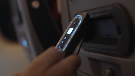 Woman-using-control-pad-of-seat-back-monitor-in-plane