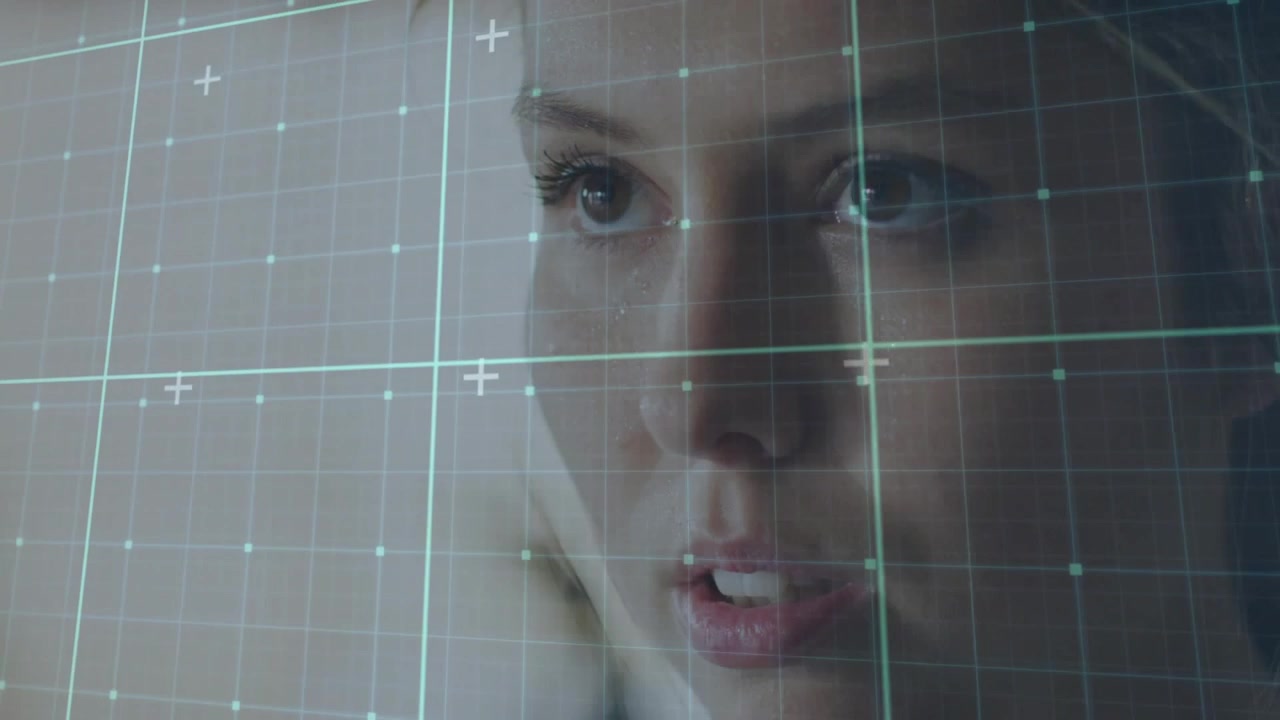 Woman lifting gaze and speaking through translucent grid overlay engaging facial markers for tech