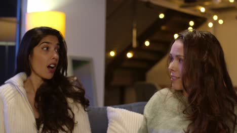 dos amigas sentadas en el sofá en casa o en un bar o café hablando y bebiendo café juntas