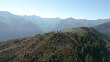 cinematic drone aerial over mountain peak with cross tilt down awesome view reaveal of summit with nice background