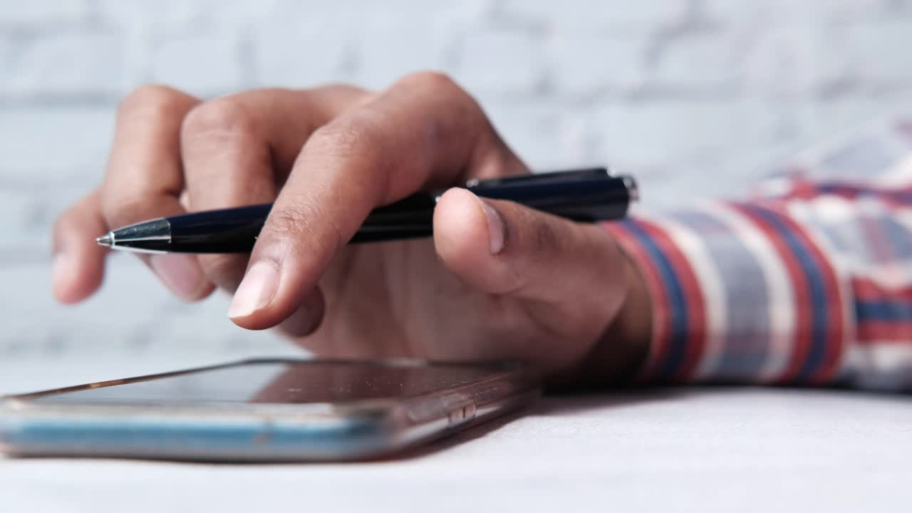 persona que utiliza un teléfono inteligente y un bolígrafo