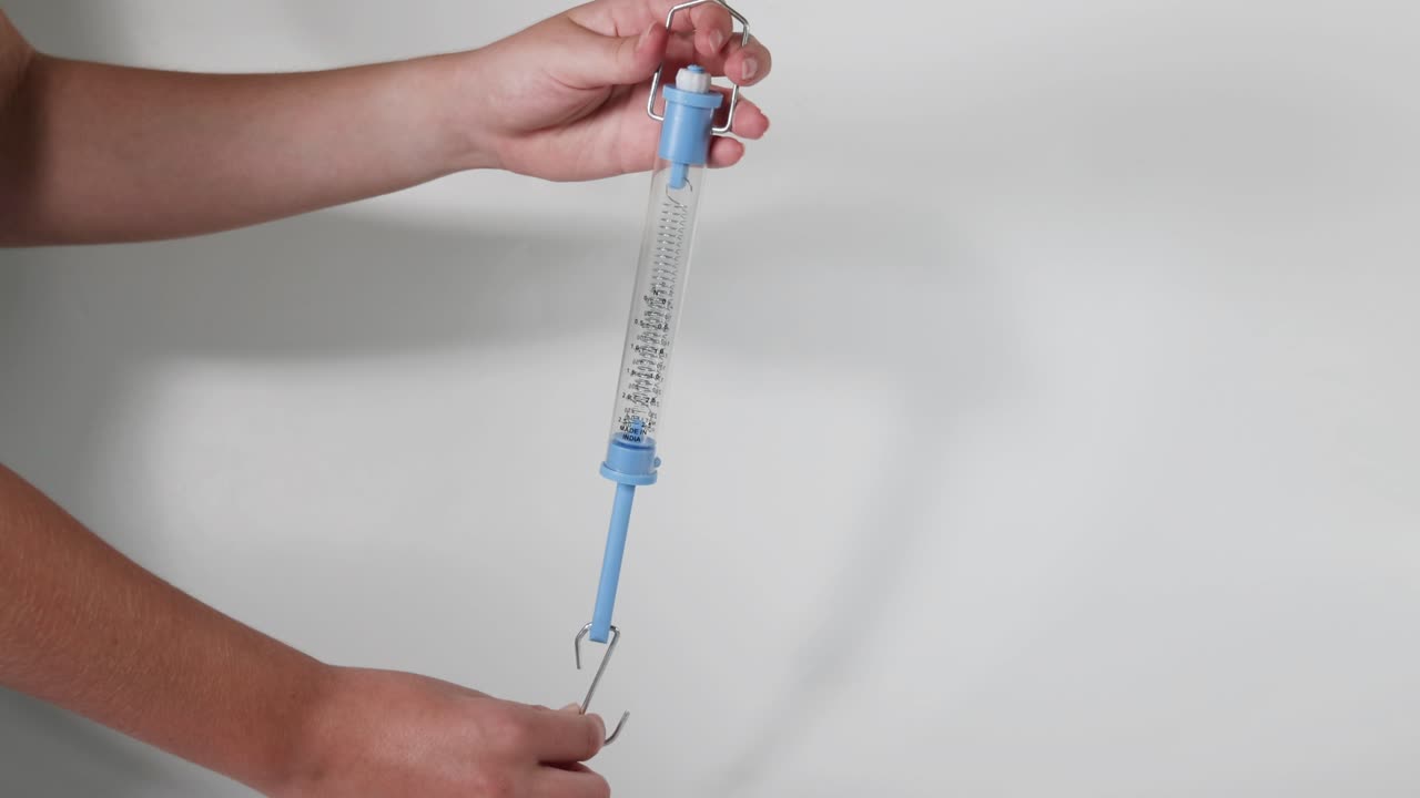 푸른 뉴턴 스프링 스케일을 보여주는 손