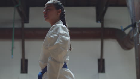 vista frontal de la chica en kimono pateando y golpeando a la cámara