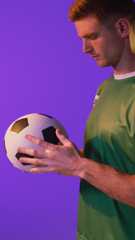 video vertical de un jugador de fútbol masculino caucásico con fútbol sobre iluminación rosa neón
