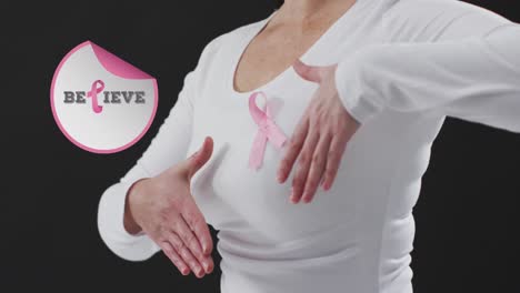 animation of believe text over caucasian woman with pink ribbon on black background