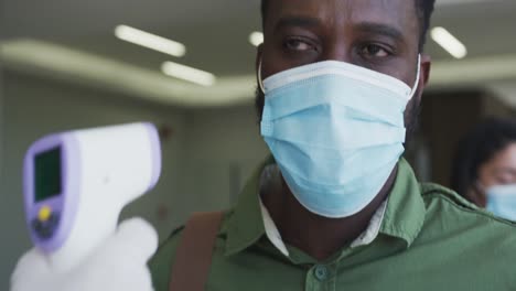 man wearing face mask getting his temperature measured