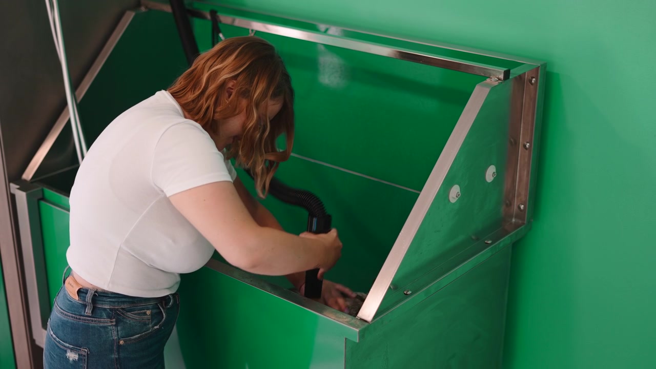 Woman Using Professional Pet Dryer to Groom Dog in Grooming Station