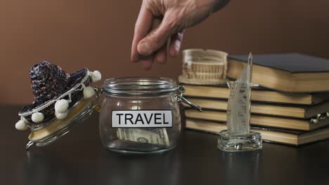 man puts coins into glass with money for travel