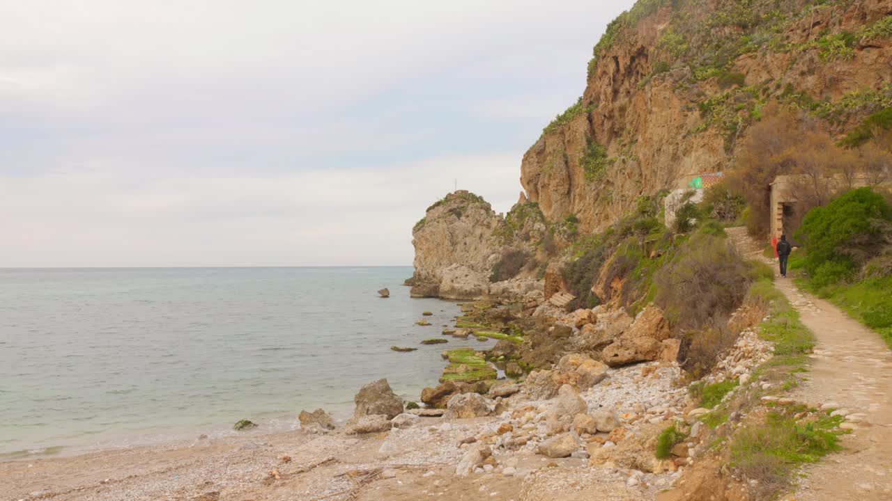 Discover a peaceful coastal landscape in Sicily, showcasing rocky shores, gentle waves, and lush greenery. The serene atmosphere invites viewers to appreciate nature's charm and tranquility.