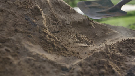 close up, slow motion, an indigenous man shoveling dirt off the underground cooking pit in the afternoon sunlight