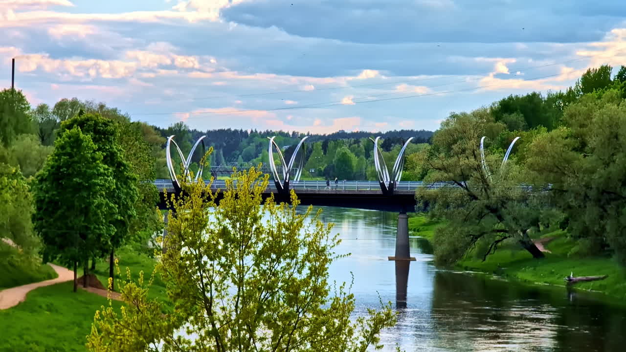 Iconic Gauja river bridge in Valmiera seen from distance between dense spring trees