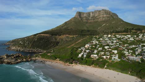 Costa-Rocosa-De-La-Playa-De-Llandudno-Y-Montaña-De-La-Mesa-Al-Atardecer-En-Ciudad-Del-Cabo,-Aérea