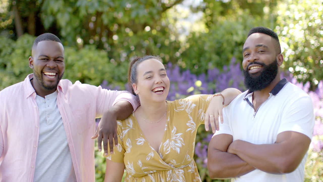 Diverse friends, men and woman, smiling and laughing in backyard garden