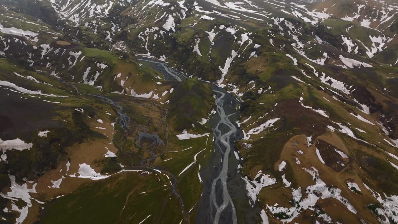 아이슬란드 의 구름 이 많고 안개 가 있는 날 에 녹는 눈 으로  ⁇ 인 산 들 을 가로질러 흐르는 강 의 공중 파노라마 전망