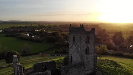 Aerial-backwards-reveal-shot-of-church-ruins-at-Burrow-Mump-with-a-beautiful-sunset-as-a-backdrop