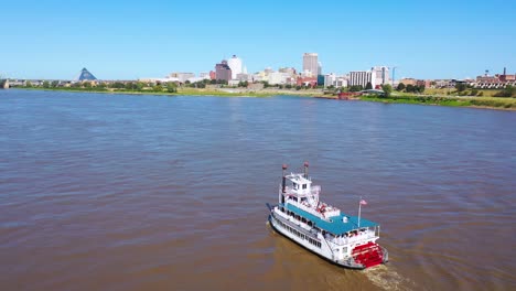 Buena-Antena-De-Un-Barco-De-Vapor-De-Rueda-De-Paletas-Subiendo-Por-El-Río-Mississippi-Con-Memphis-Tennessee-En-El-Fondo