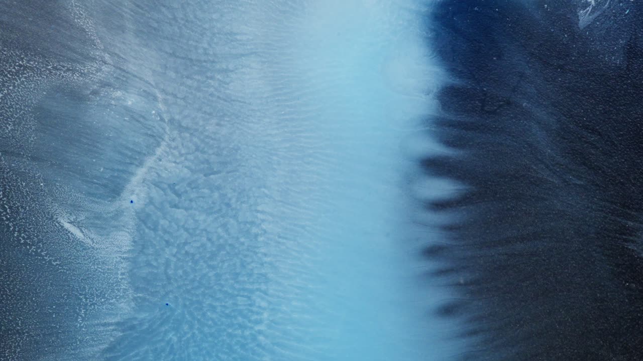 Black and blue alcoholic ink blend creates abstract textures in close-up macro view