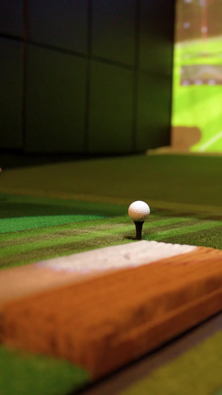 Primo piano dal basso di un golfista che colpisce una palla all'interno di un simulatore di realtà virtuale.