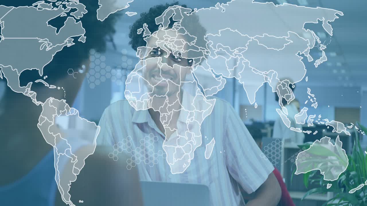 Man smiling and gesturing near laptop, initiating fading world map overlay for business insight