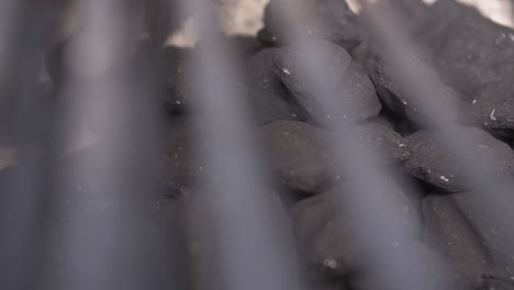 slider move on close up bbq charcoal briquettes with grilling grates in foreground