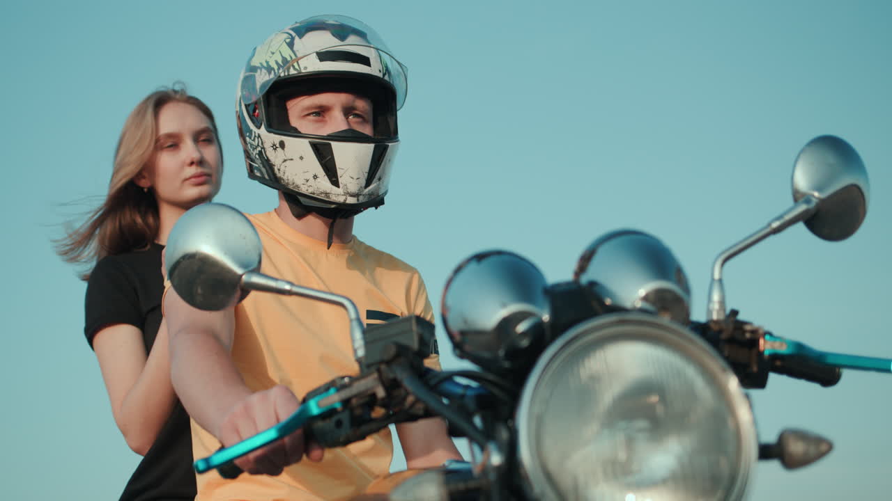 un chico y una chica están sentados en una motocicleta mirando a lo lejos 1