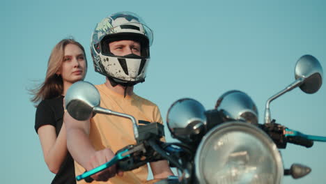 un chico y una chica están sentados en una motocicleta mirando a lo lejos 1