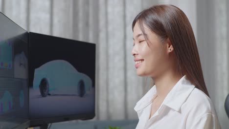 close up of asian female automotive designer smiling to camera while working on 3d model of ev car on the desktop computers in the studio