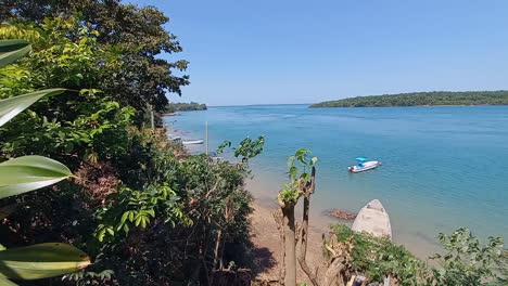 Beautiful-cinematographic-image-of-the-blue-sea-that-separates-the-islands-of-Bubaque-and-Rubane,-sea-of-calm-waters,-with-palm-trees-and-dense-bush-almost-touching-the-sea