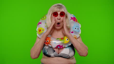 Shocked-senior-pensioner-woman-tourist-in-swimsuit-on-chroma-key,-wow-exciting-surprise-reaction