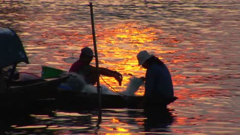 vietnamese fishermen head out in their canoe at dusk