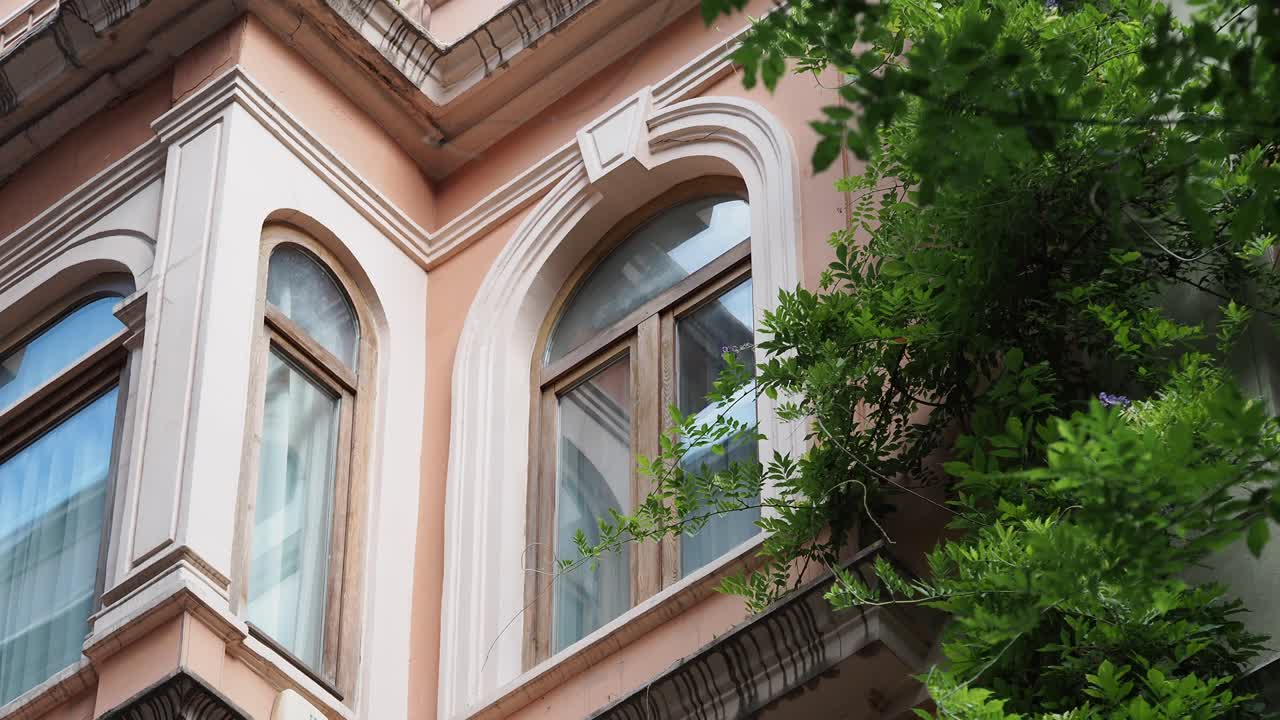 Close-up of a traditional building's facade with arched windows and lush green foliage