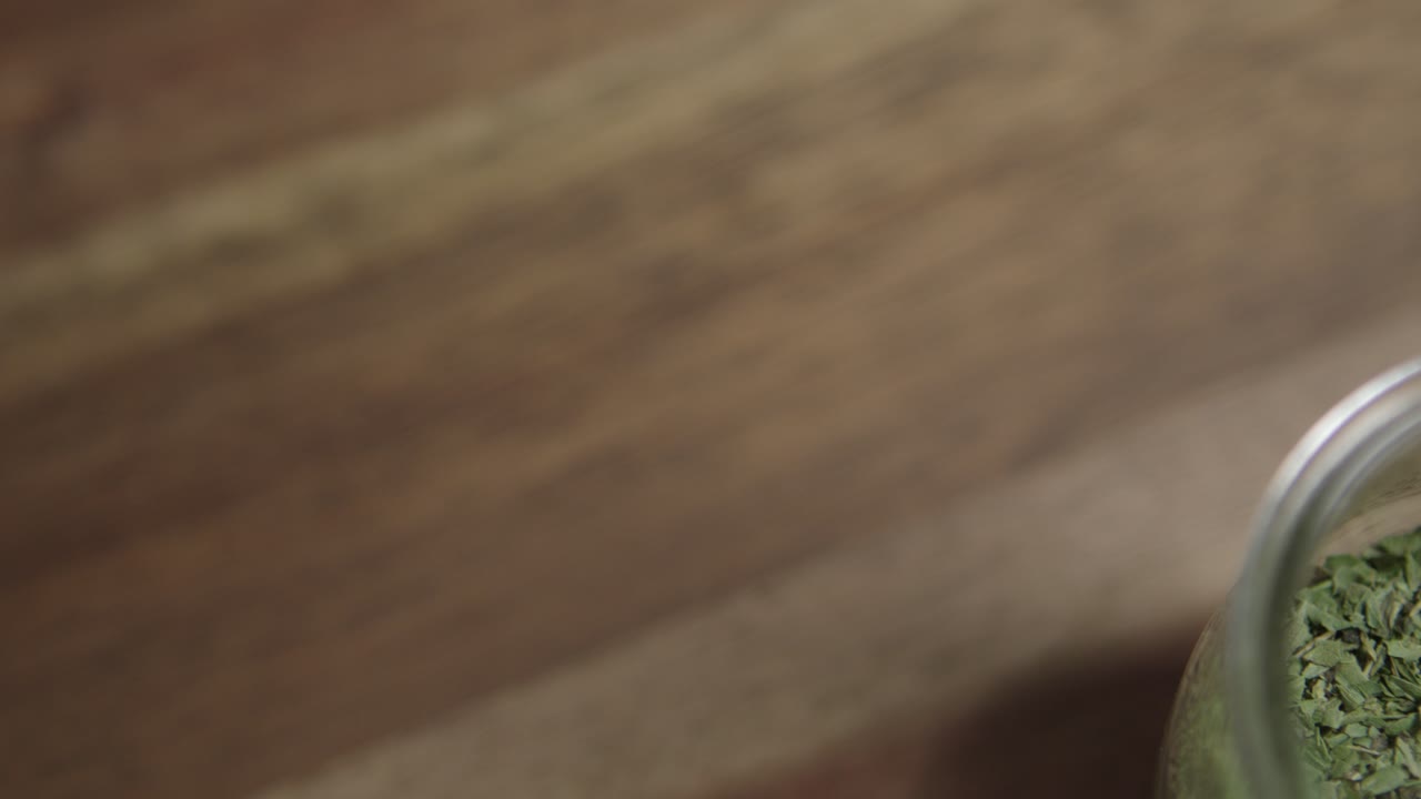 disparo en primer plano de orégano seco sentado en un pequeño frasco de vidrio