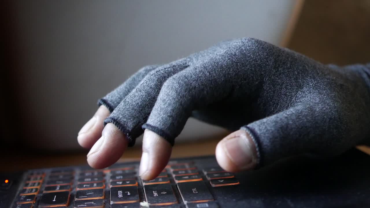 Hand with glove typing on a laptop keyboard