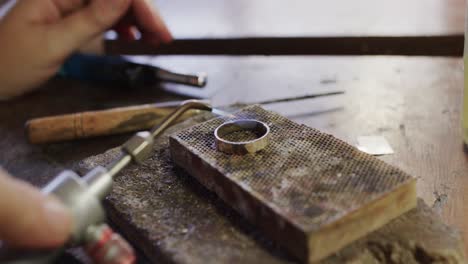 Caucasian-female-worker-shaping-ring-with-blowtorch-in-workshop-in-slow-motion